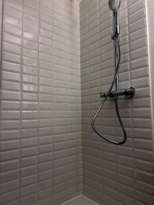 Handheld showerhead mounted on a rail in a tiled shower stall