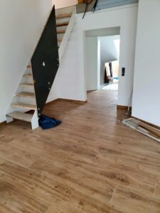Innenansicht einer im Bau befindlichen Treppe mit freiliegender Unterkonstruktion und einer schwarzen Platte, die sich über die Stufen erstreckt.